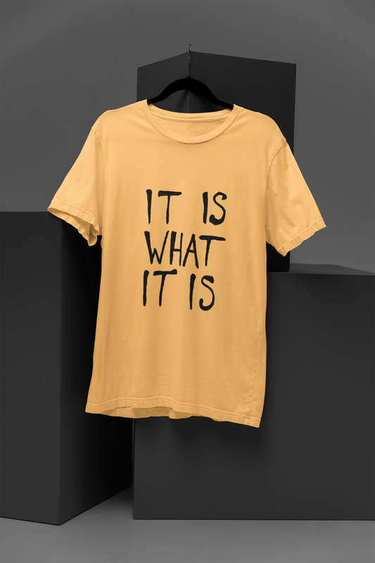 FOMO Fashions It Exists T Shirt: beige tee with minimalist gray"It is what it is" text print across the chest.